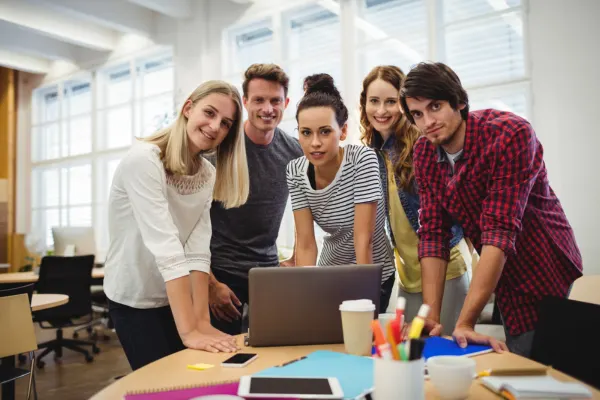 A young, diverse team collaborating around a laptop in a flexible coworking for startups office environment.