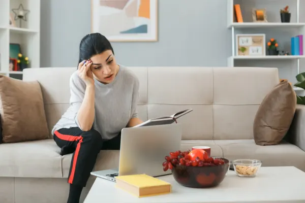 Stressed woman working from home on a couch; see how a dedicated coworking space affects productivity levels.