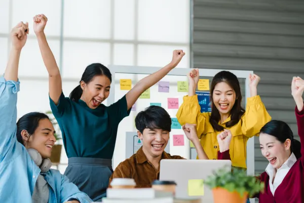 Excited office colleagues celebrating success; a vibrant coworking space affects productivity and team morale.