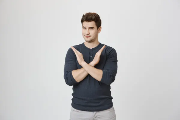 A man standing confidently while crossing his arms in an X gesture, symbolizing firm personal boundaries.